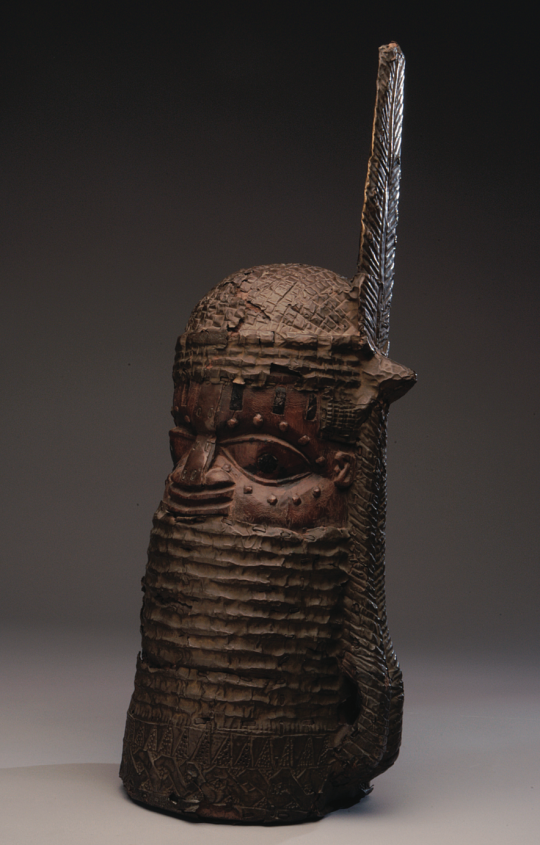 图6: 佚名埃多族艺术家，尼日利亚，酋长纪念头部雕塑（uhun-mwun-elao），19世纪末20世纪初，木头、黄铜、椰子壳镶嵌物， 65.1 cm x 24.8 cm，Chazen艺术博物馆，2004.86, 通过J. David and Laura Seefriend Horsfall 捐赠金购入。